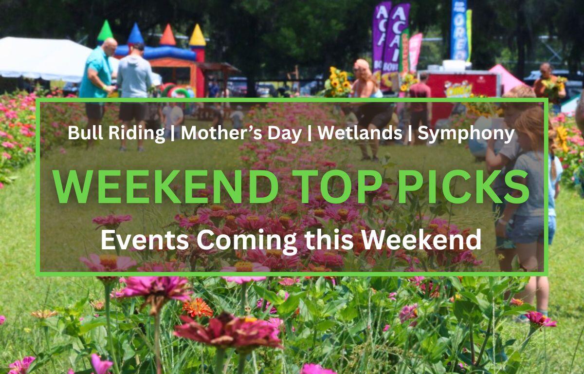Outdoor festival in a park with pink zinnias in the foreground and people visiting tents and banners in the background, sunny day. In the foreground is a brown box with a green border. White and green text inside of the box read, "Bull Riding | Mother's Day | Wetlands | Symphony. WEEKEND TOP PICKS. Events Coming this Weekend."
