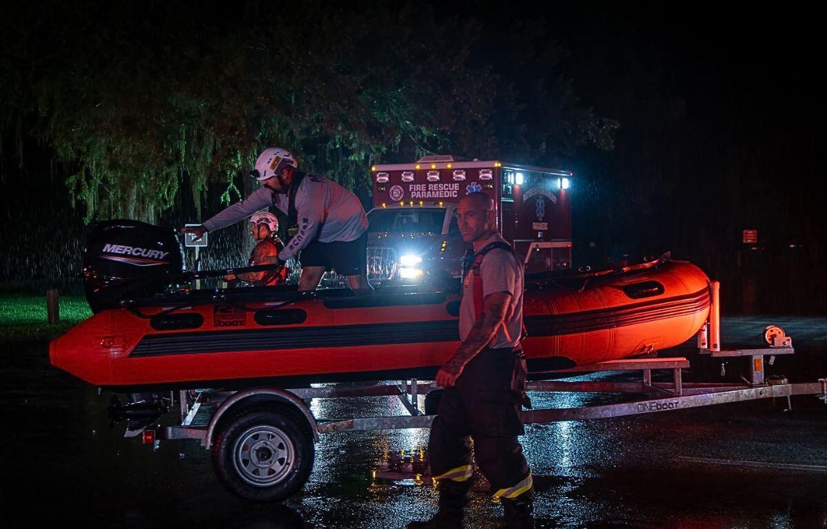 A image of a rescue boat on a boat trailer in front of an ambulance at nighttime.
