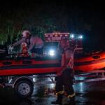 A image of a rescue boat on a boat trailer in front of an ambulance at nighttime.