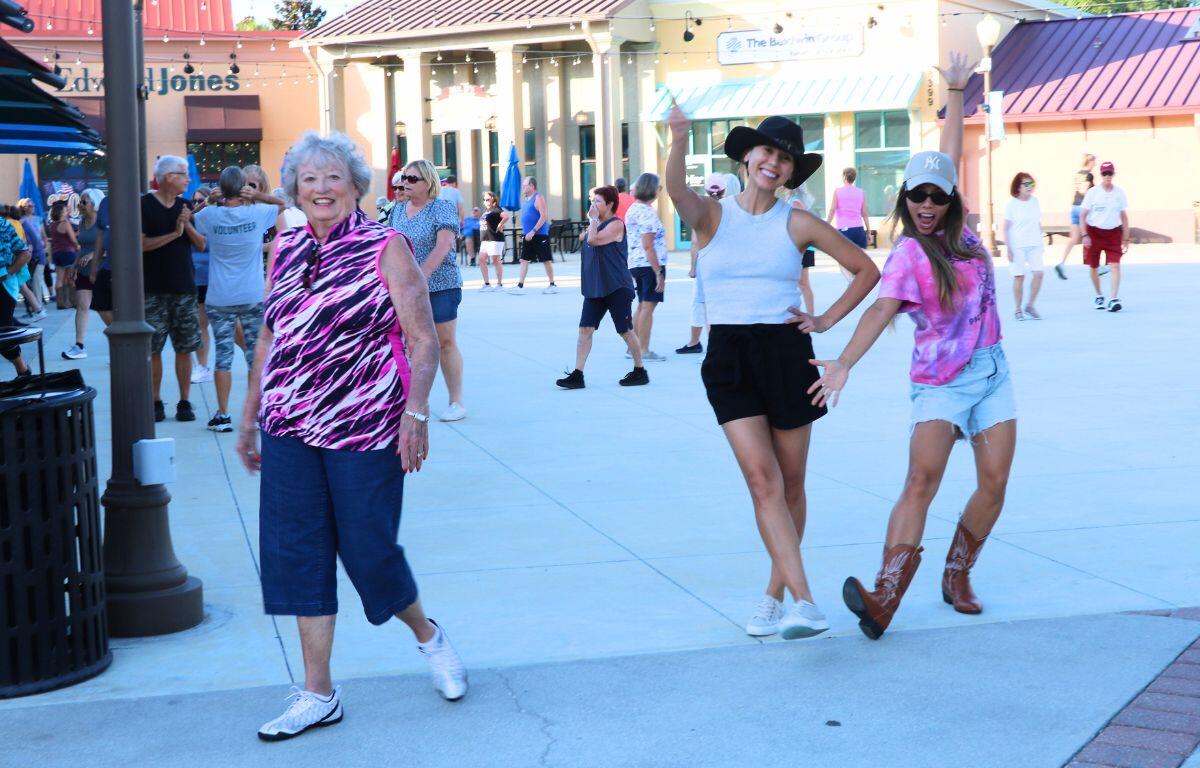 Three ladies pose together in a shopping plaza with line-dancing and athletic outfits.