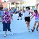 Three ladies pose together in a shopping plaza with line-dancing and athletic outfits.