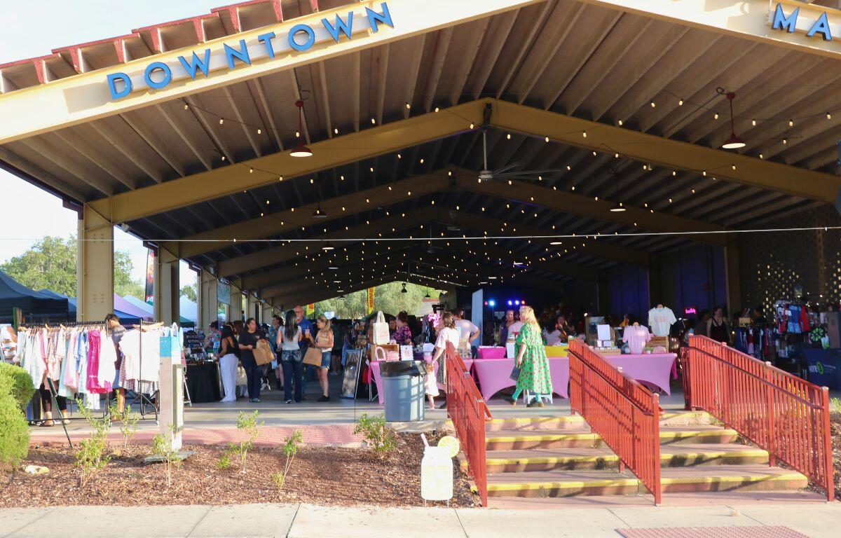 A large pavilion features a large display of vendors with crowds of guests walking through isles of booths.