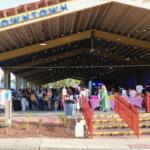 A large pavilion features a large display of vendors with crowds of guests walking through isles of booths.