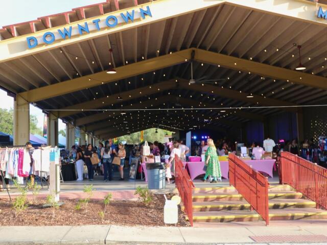 A large pavilion features a large display of vendors with crowds of guests walking through isles of booths.