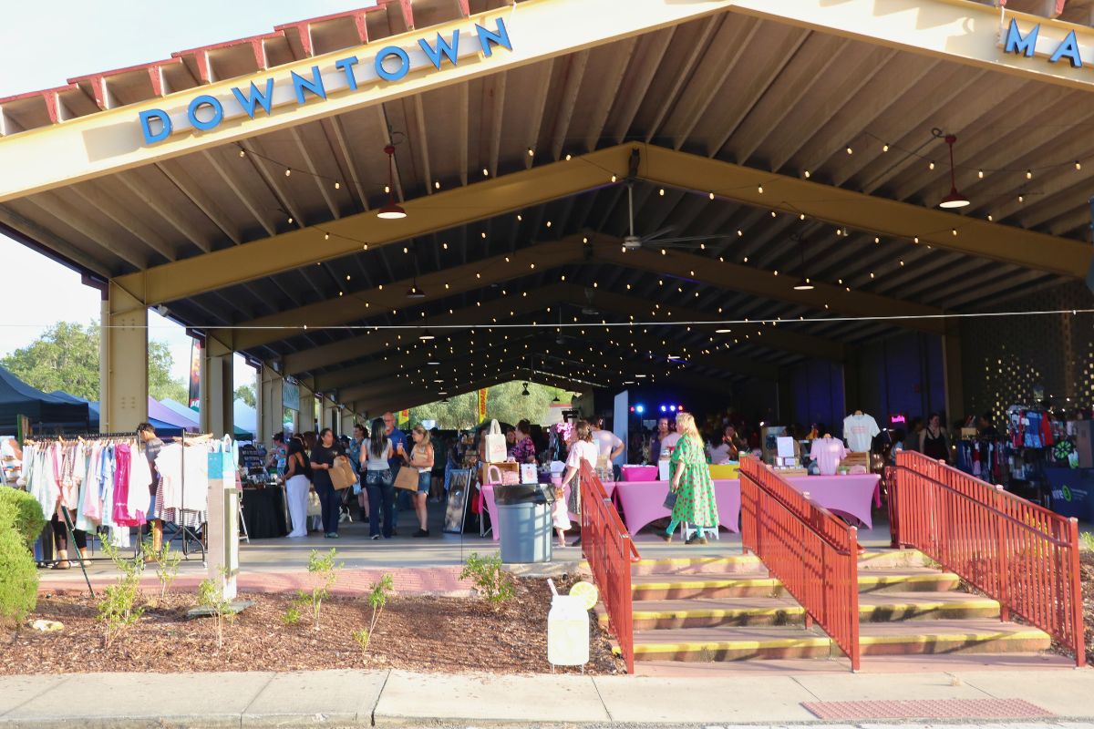 A large pavilion features a large display of vendors with crowds of guests walking through isles of booths.