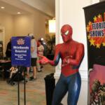 A large Spiderman statue stands in an open hallway with tall, black banners reading, "Florida Toy Shows & Expos."