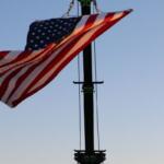 A flag is suspended in the air by a crane. The flag flows with the wind.