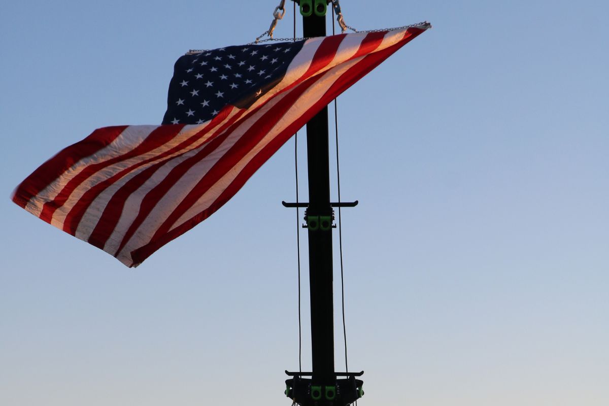 A flag is suspended in the air by a crane. The flag flows with the wind.