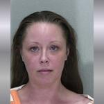 A mugshot of a woman with brown hair in a orange and white striped jumpsuit.