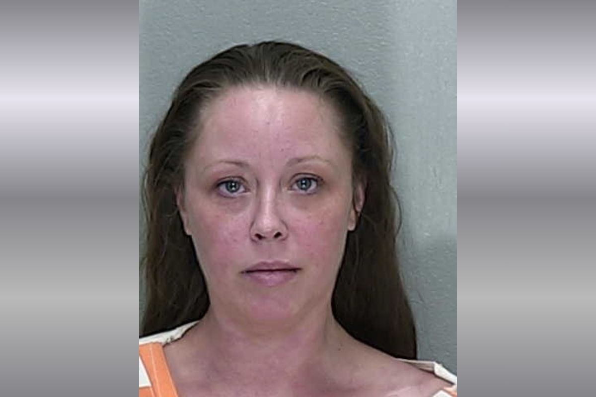 A mugshot of a woman with brown hair in a orange and white striped jumpsuit.