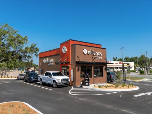 A colored image of a brown and orange coffee shop with an occupied drive-thru.