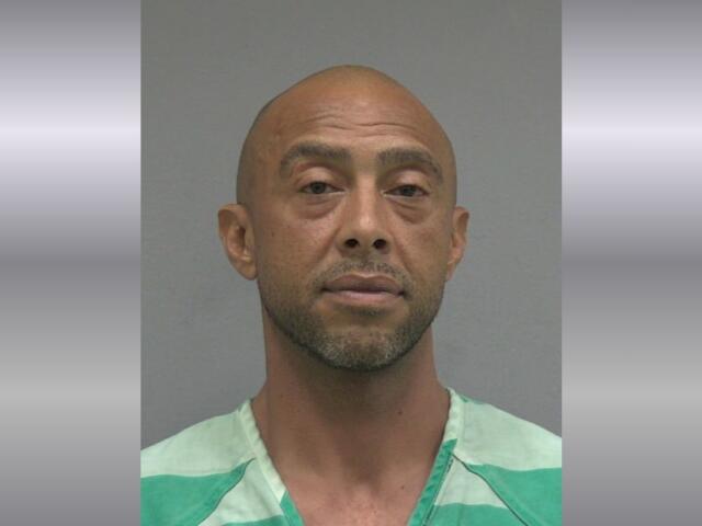 Mugshot of a bald man wearing a green jail uniform, facing the camera with a neutral expression.