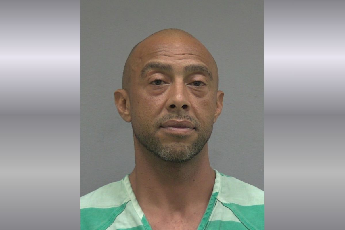 Mugshot of a bald man wearing a green jail uniform, facing the camera with a neutral expression.