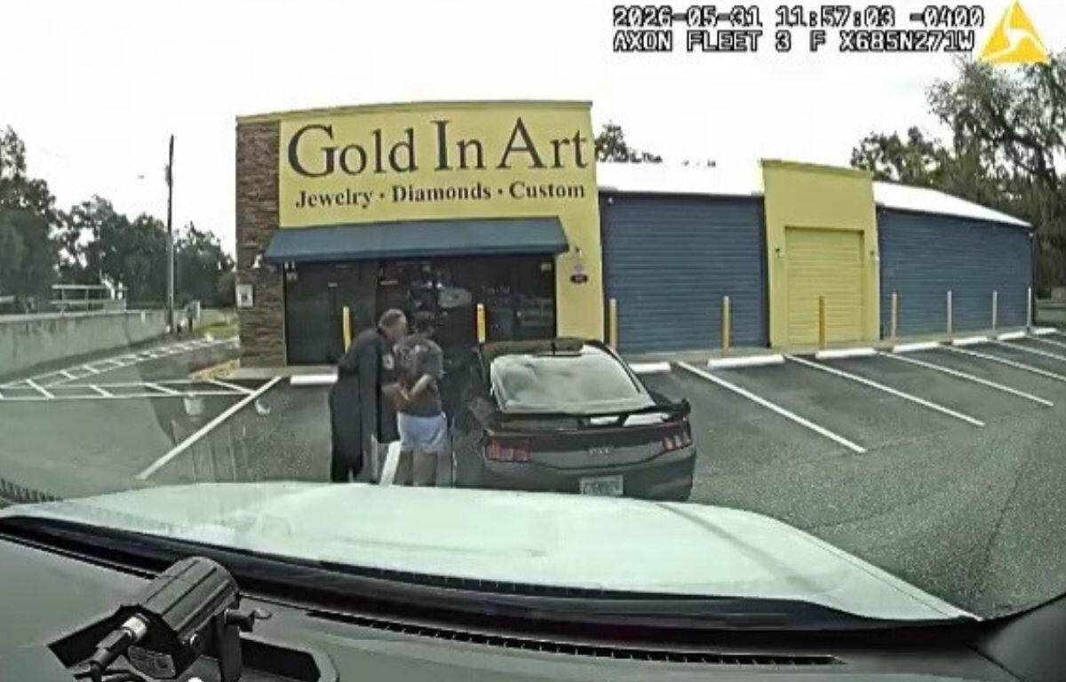 Dashcam footage of a man being arrested by police outside of a black Ford Mustang.