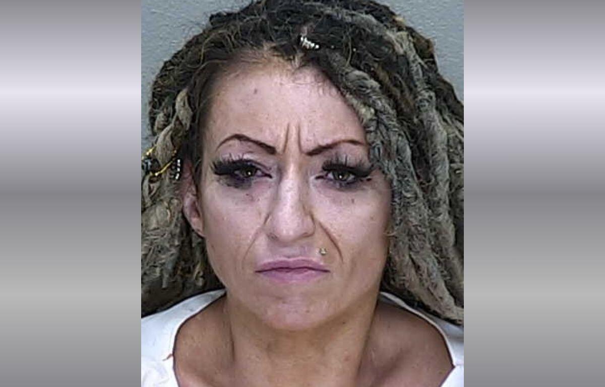 A woman with dreadlocks and long eyelashes in a white jumpsuit.