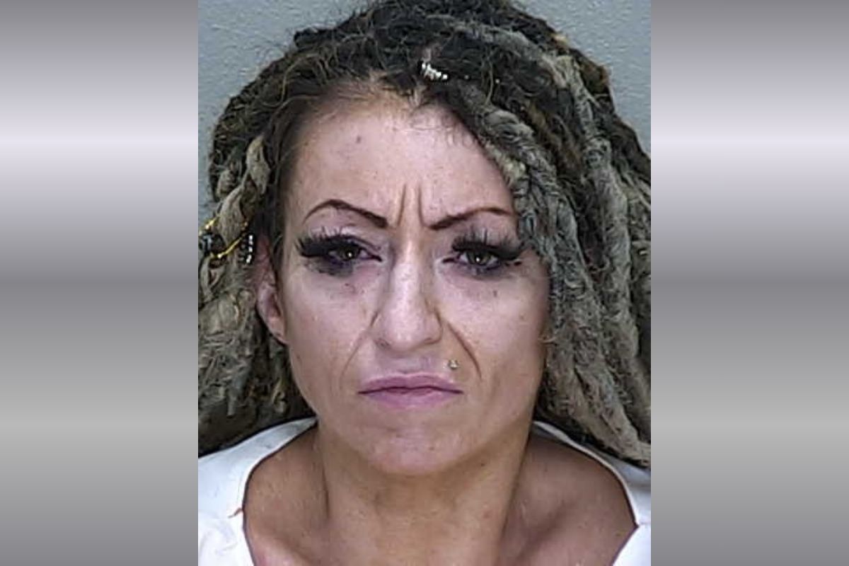 A woman with dreadlocks and long eyelashes in a white jumpsuit.