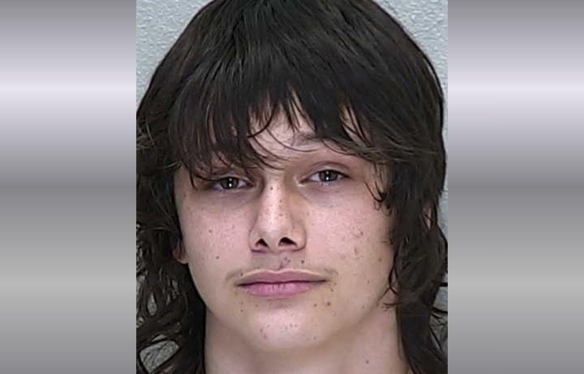 A mugshot of a white teen with shorter black hair and bangs.