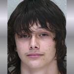 A mugshot of a white teen with shorter black hair and bangs.