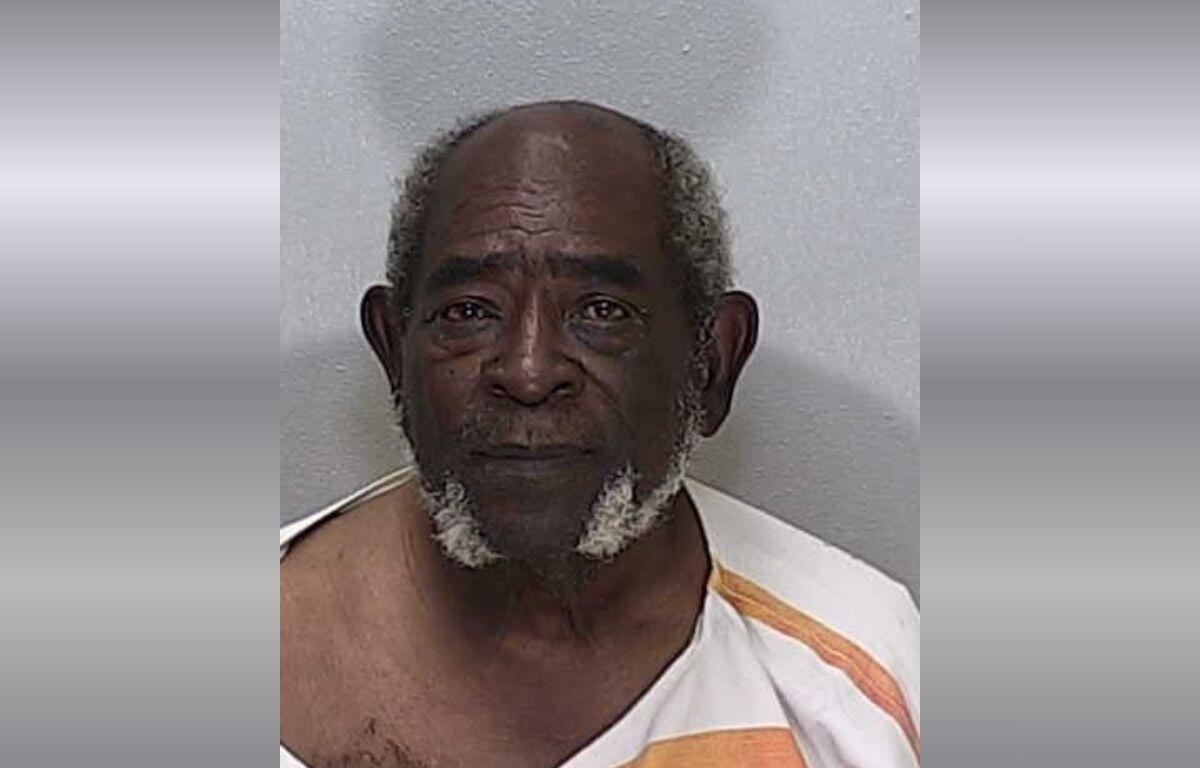 An older African American man in an orange and white striped jumpsuit.