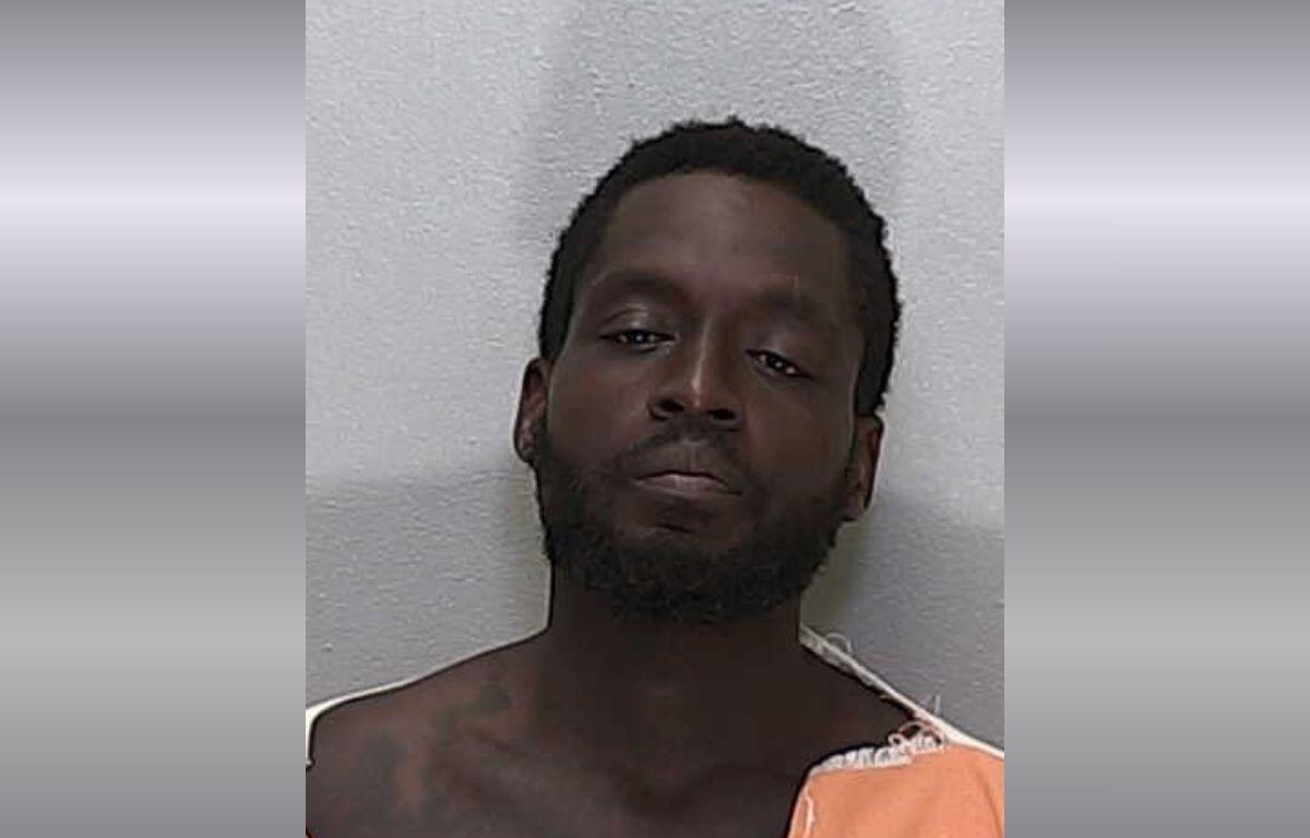 An African American man with short hair in an orange and white striped jumpsuit.