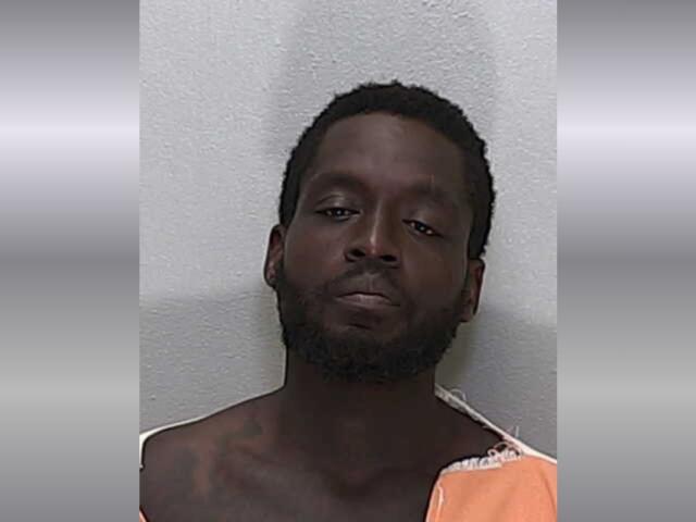 An African American man with short hair in an orange and white striped jumpsuit.