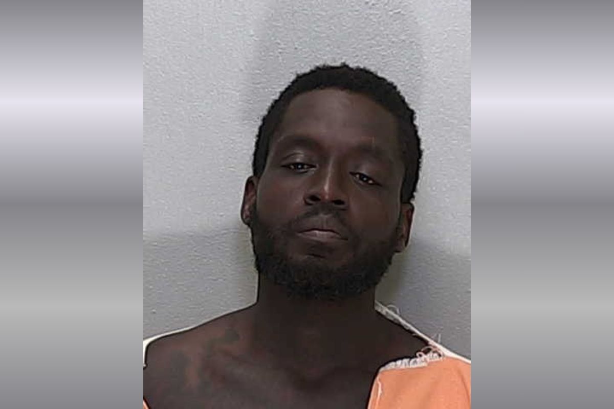 An African American man with short hair in an orange and white striped jumpsuit.