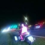 A still from body cam footage of a man in a pink business suit sitting on a silver trike.