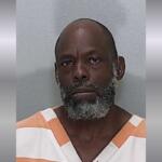A mugshot of an African American man with a gray beard.