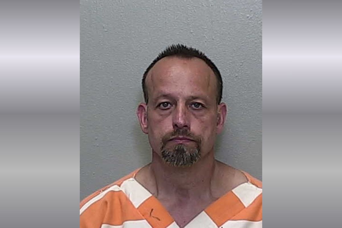 A white man with short hair in an orange and white striped jumpsuit.