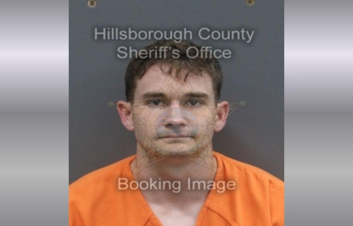 A white man with short brown hair in an orange jumpsuit.