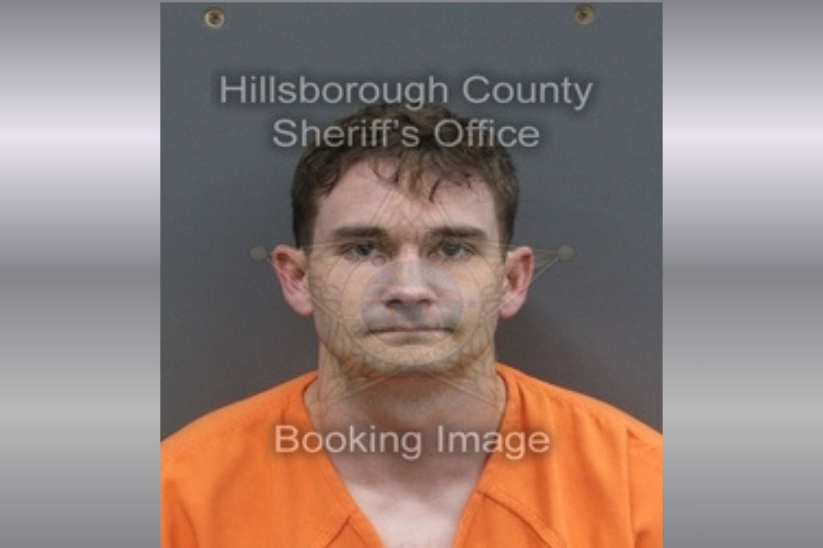 A white man with short brown hair in an orange jumpsuit.