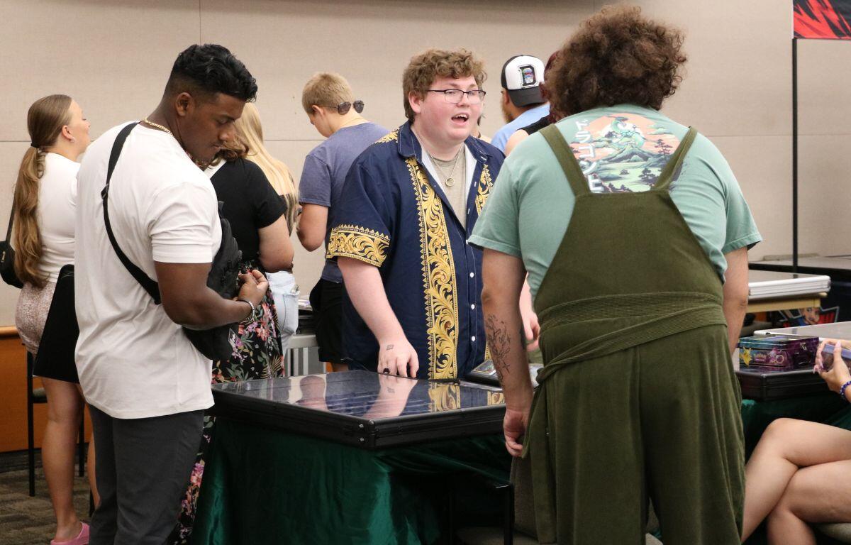 Group of attendees gathered around a glass display table at an indoor event.