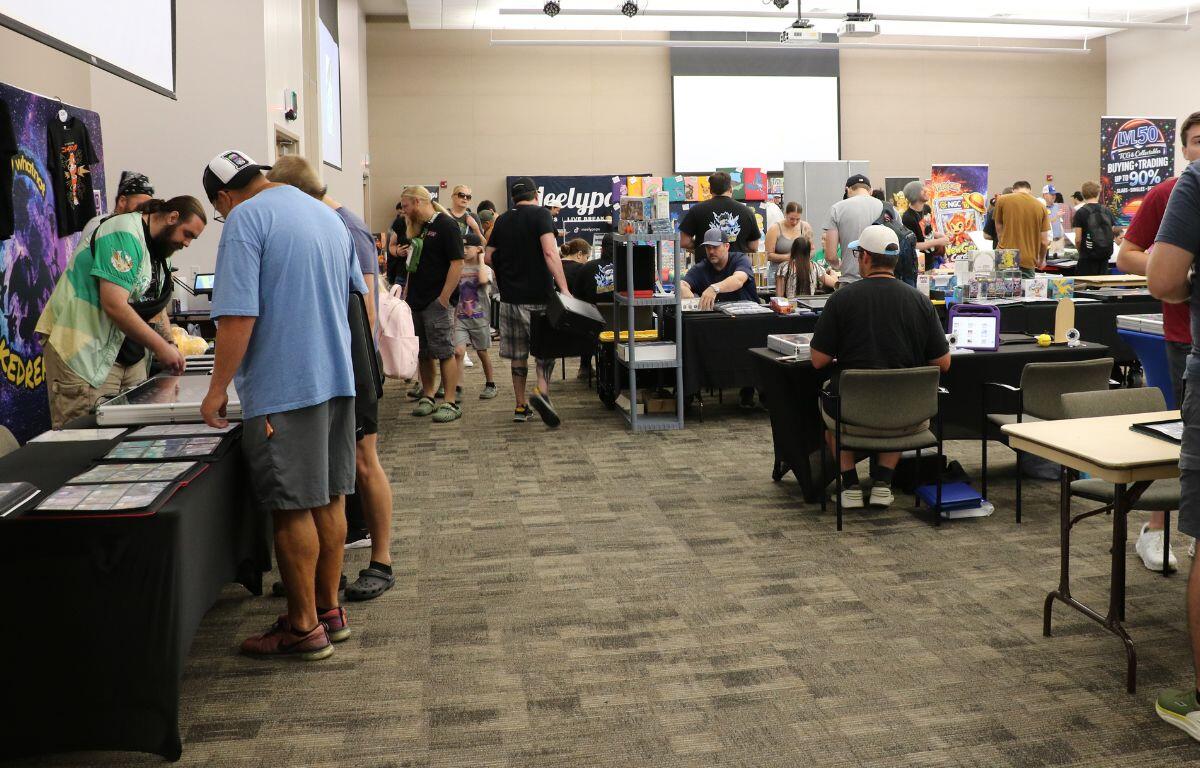 A crowd of people walk through and indoor venue exploring vendors.