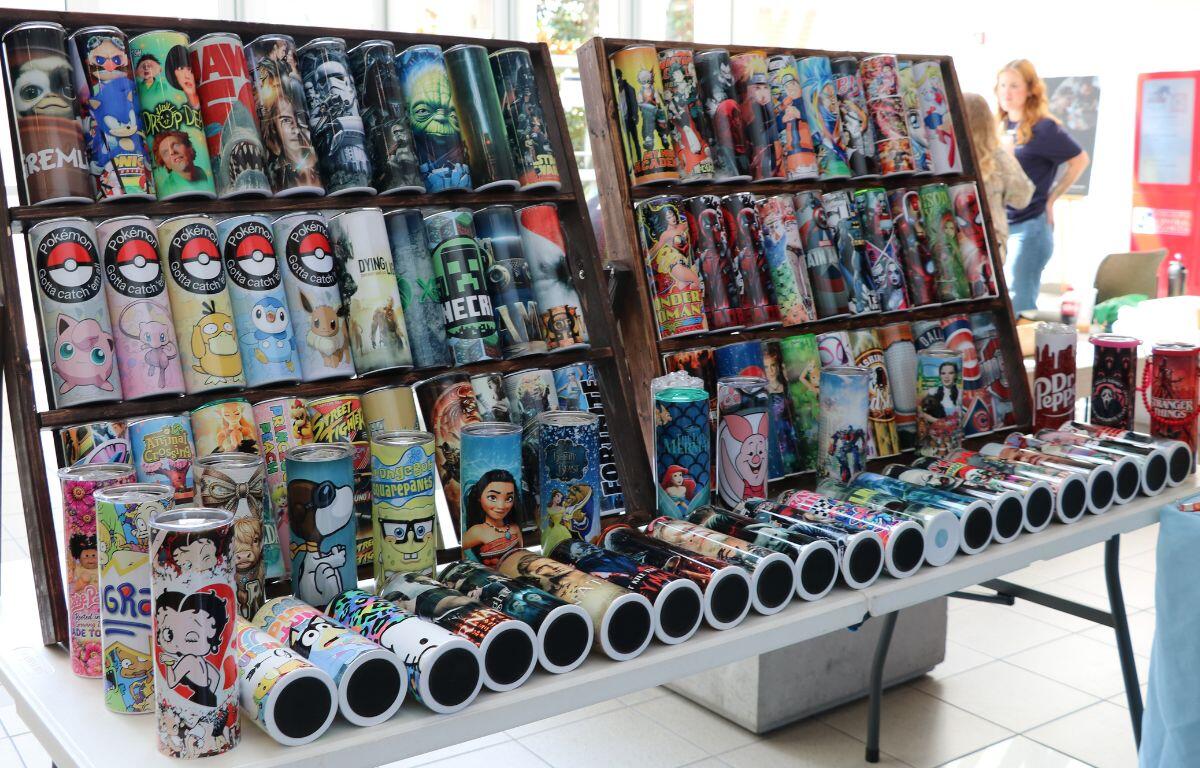 Colorful display of tumblers with cartoon character designs arranged on shelves at a market stall.