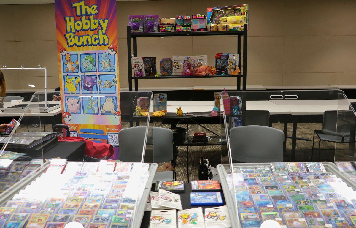 A retail display area with a bright banner reading 'The Hobby Bunch' beside shelves of boxed toys and collectibles on black metal racks.