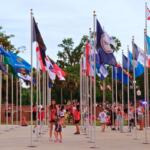 People walk through a courtyard with flags in a Veteran Memorial Park.