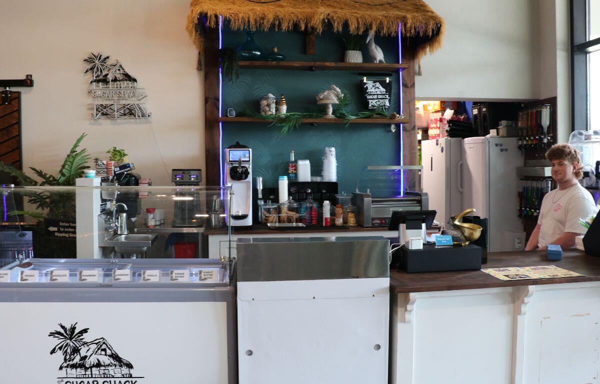 Food vendor with ice cream stands in open dining hall with man sitting behind the counter.