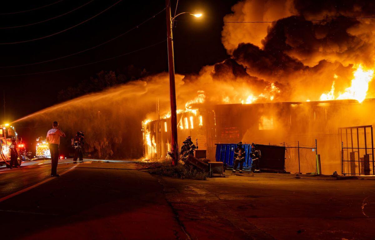 Firefighters work to extinguish the flames of a large commercial building.