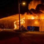 Firefighters work to extinguish the flames of a large commercial building.