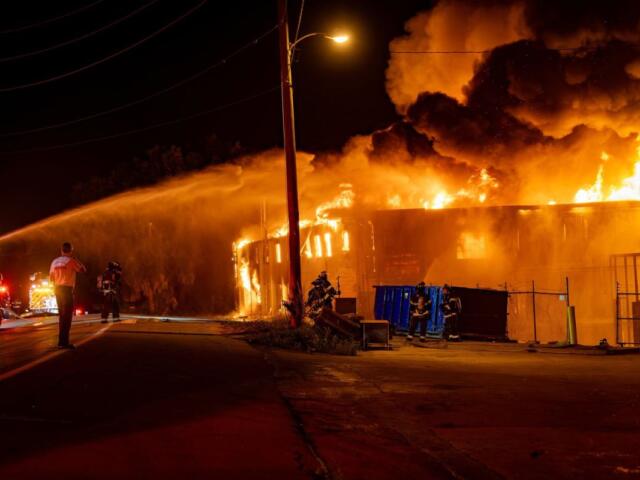 Firefighters work to extinguish the flames of a large commercial building.