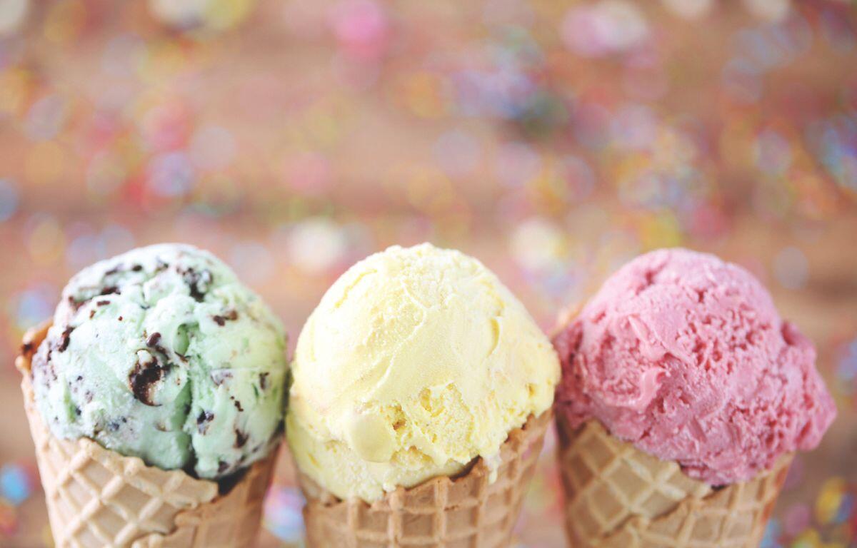 A close-up of three ice cream cones, mine chocolate chip on the left, vanilla in the middle, and strawberry on the right.