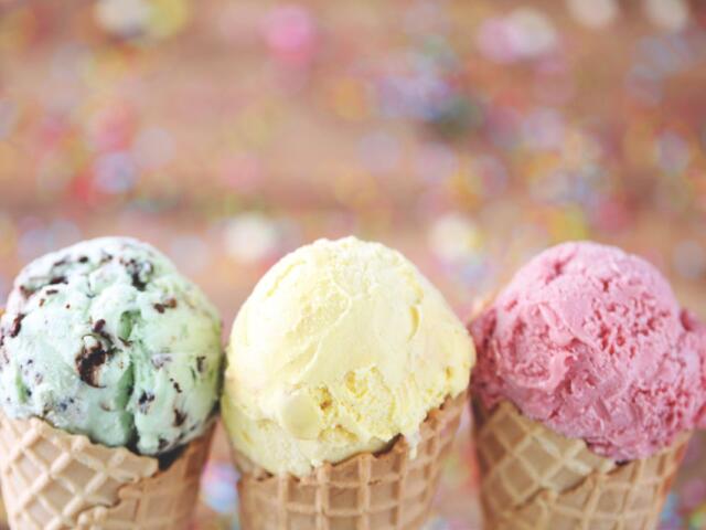 A close-up of three ice cream cones, mine chocolate chip on the left, vanilla in the middle, and strawberry on the right.