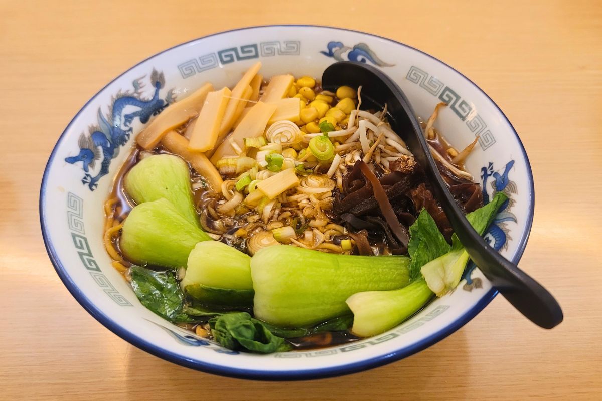 A bowl of ramen filled with vegetables on a table.