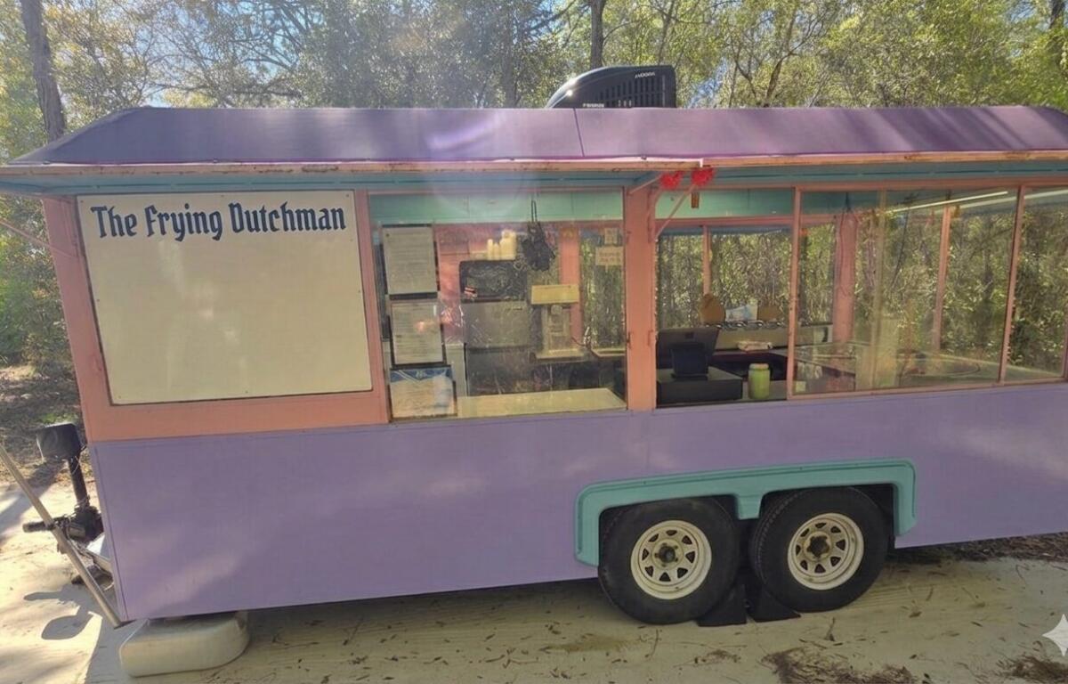 Pastel purple food cart with pink trim reading 'The Frying Dutchman' and large glass serving windows in an outdoor setting
