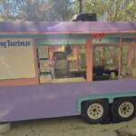 Pastel purple food cart with pink trim reading 'The Frying Dutchman' and large glass serving windows in an outdoor setting