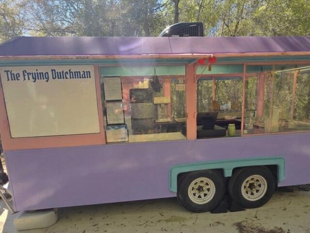 Pastel purple food cart with pink trim reading 'The Frying Dutchman' and large glass serving windows in an outdoor setting