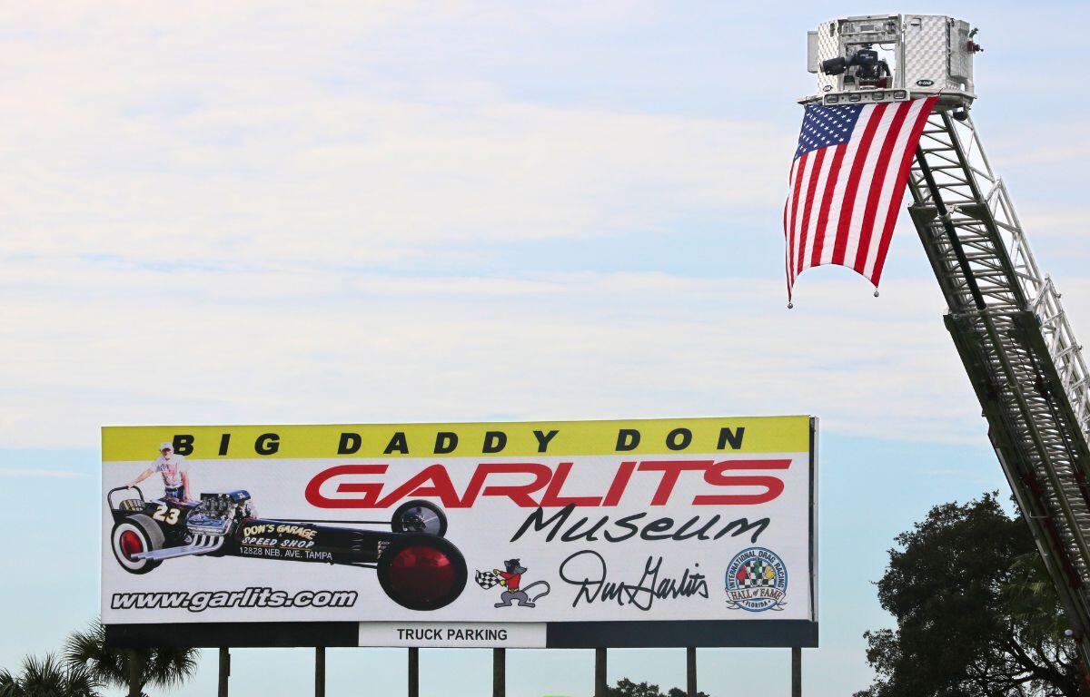 A large billboard advertises the Don Garlits Museum. An American flag lifted on a crane next to it.