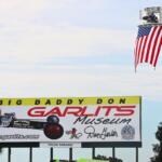 A large billboard advertises the Don Garlits Museum. An American flag lifted on a crane next to it.