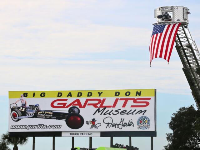 A large billboard advertises the Don Garlits Museum. An American flag lifted on a crane next to it.