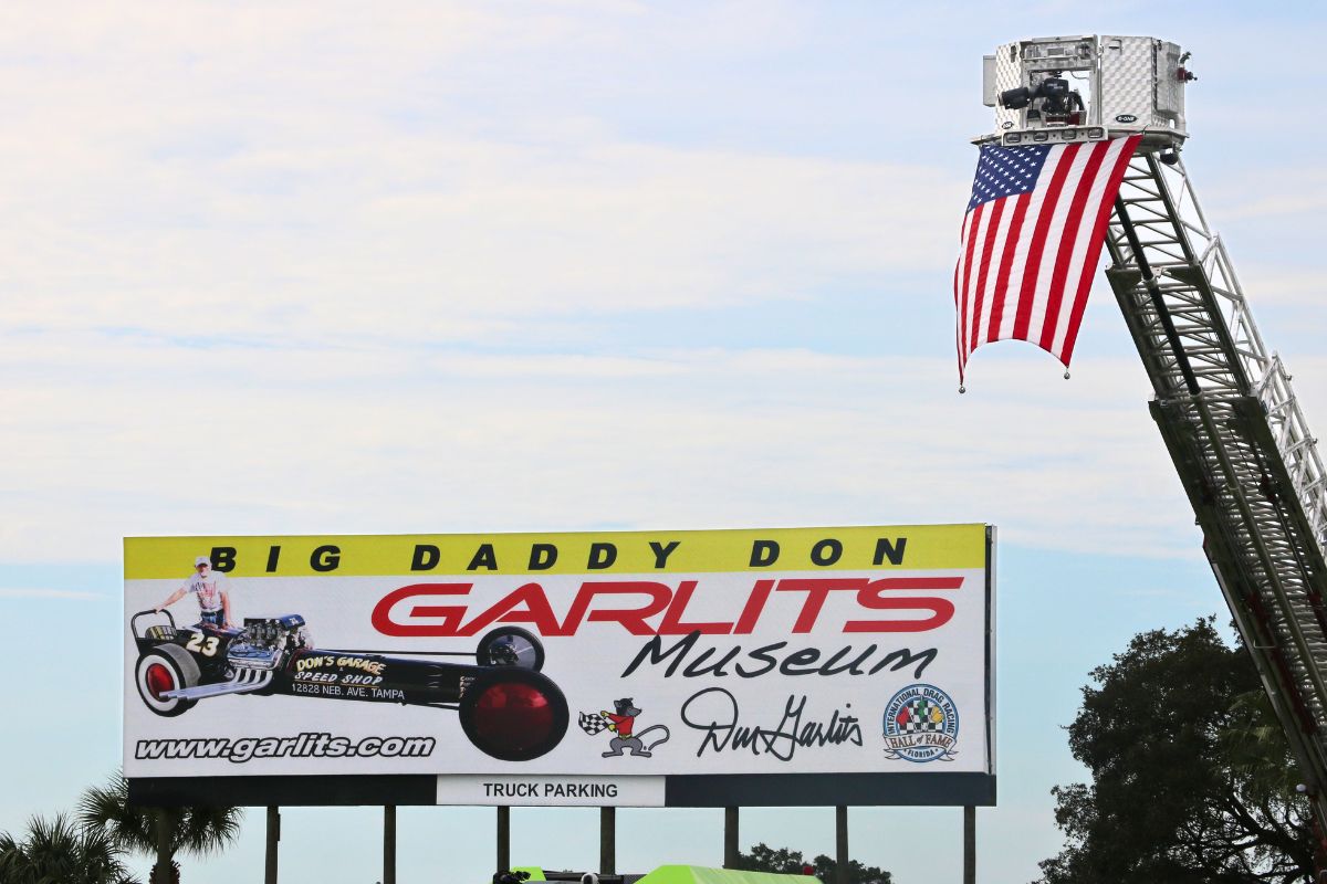 A large billboard advertises the Don Garlits Museum. An American flag lifted on a crane next to it.
